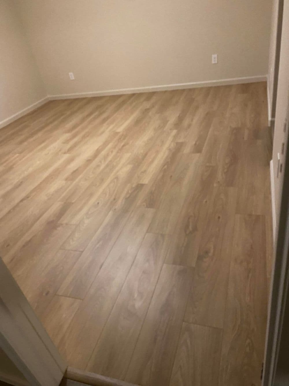 Empty room with light wood flooring and neutral walls, ready for furnishing.