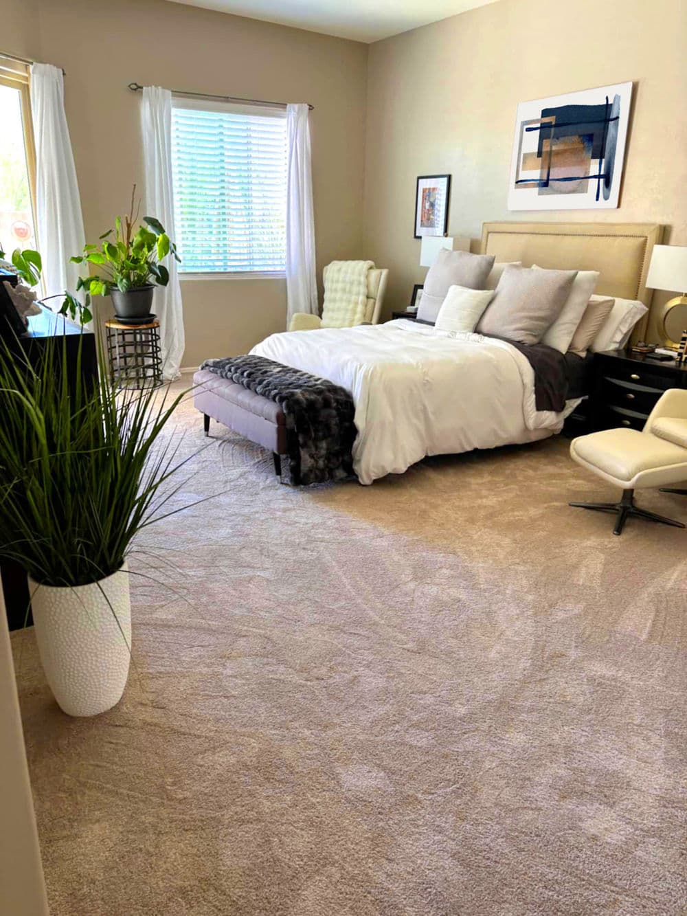 Cozy bedroom with a large bed, stylish decor, potted plants, and natural light.